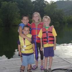 Children Smiling on Deck Near Lake